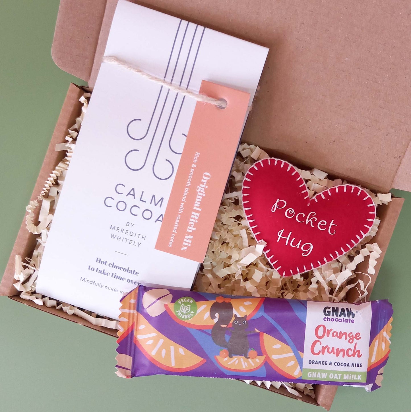 Gift box containing a felt heart pocket hug, a sachet of hot chocolate and a bar of orange oat milk chocolate