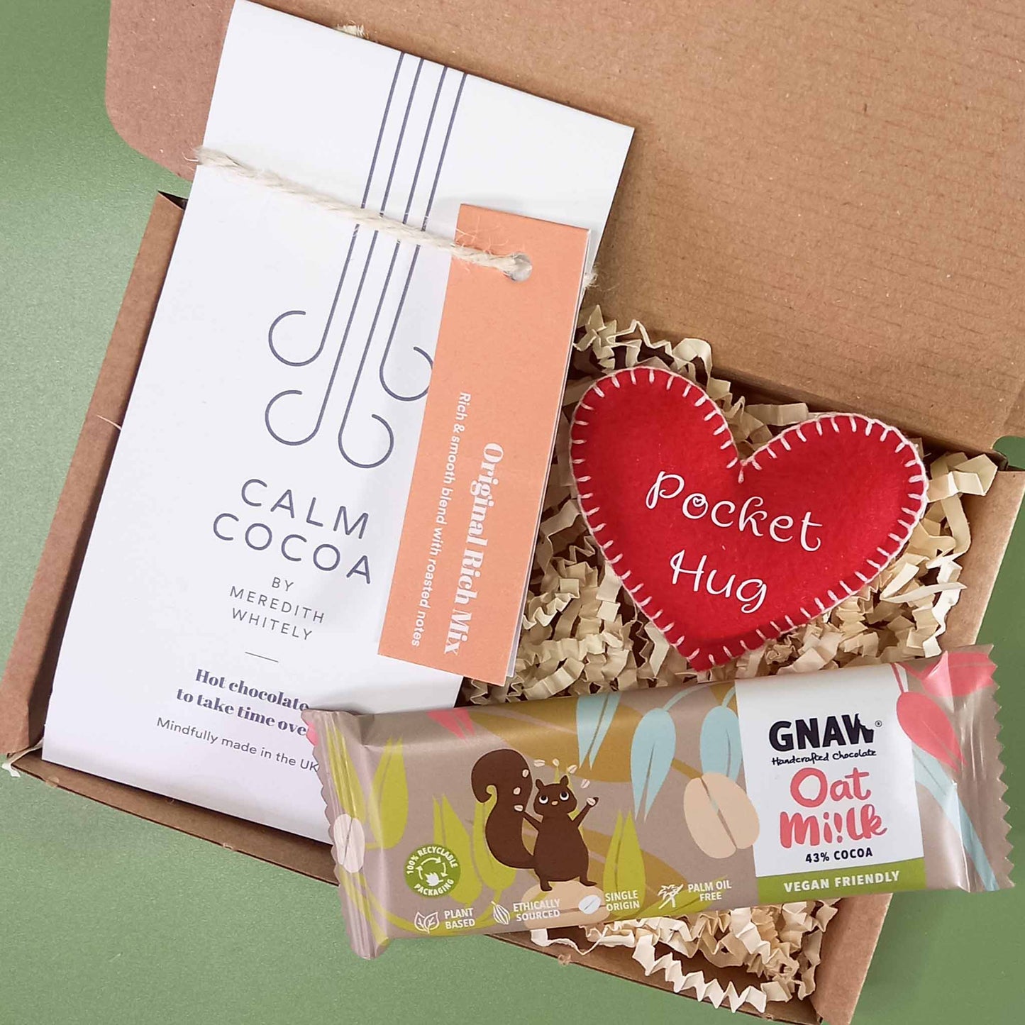 Gift box containing a vegan friendly felt pocket hug heart , a 2 serving sachet of vegan calm cocoa hot chocolate and and small oat milk chocolate bar