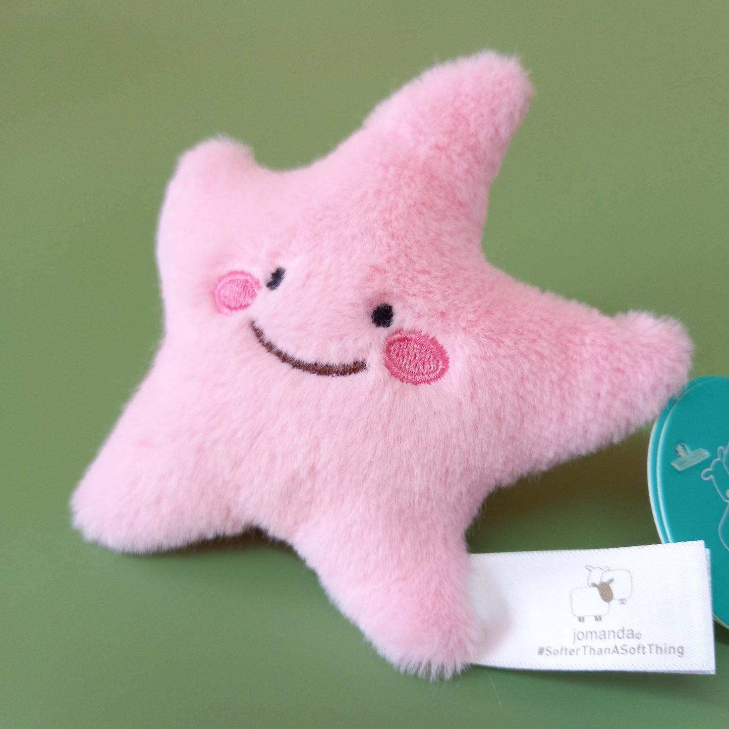 Closeup of pink starfish toy with embroidered face
