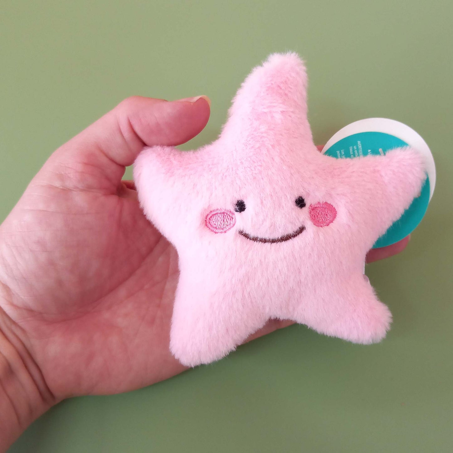 Hand holding pink starfish soft toy