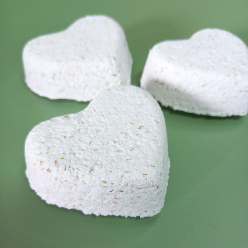 Three heart-shaped white bath bombs on a green background