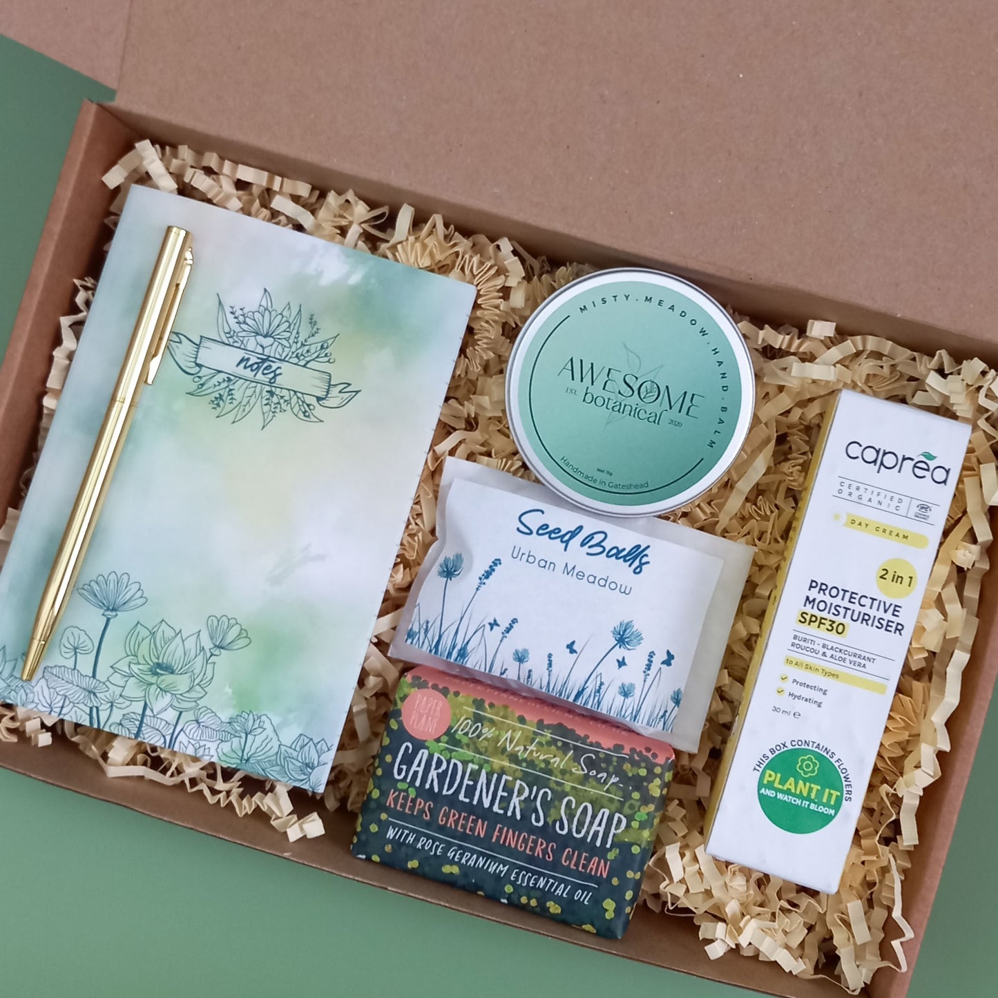 Gardener's gift box containing a notebook and gold pen, gardener's soap bar, pack of see balls, solid hand balm and SPF moisturiser with plantable packaging