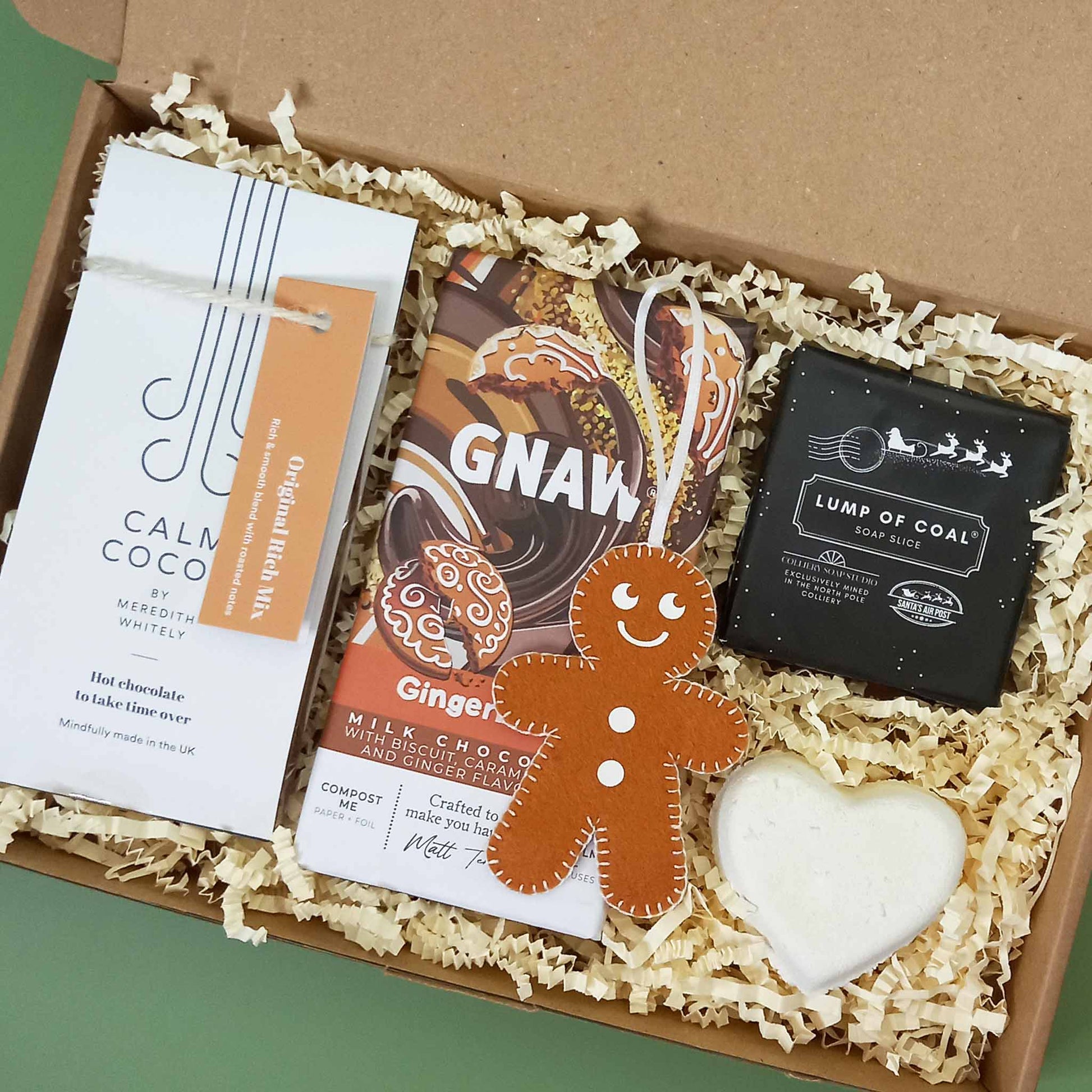 A gingerbread themed Christmas gift box containing hot chocolate, soap, bath bomb, chocolate bar and felt gingerbread man tree decoration