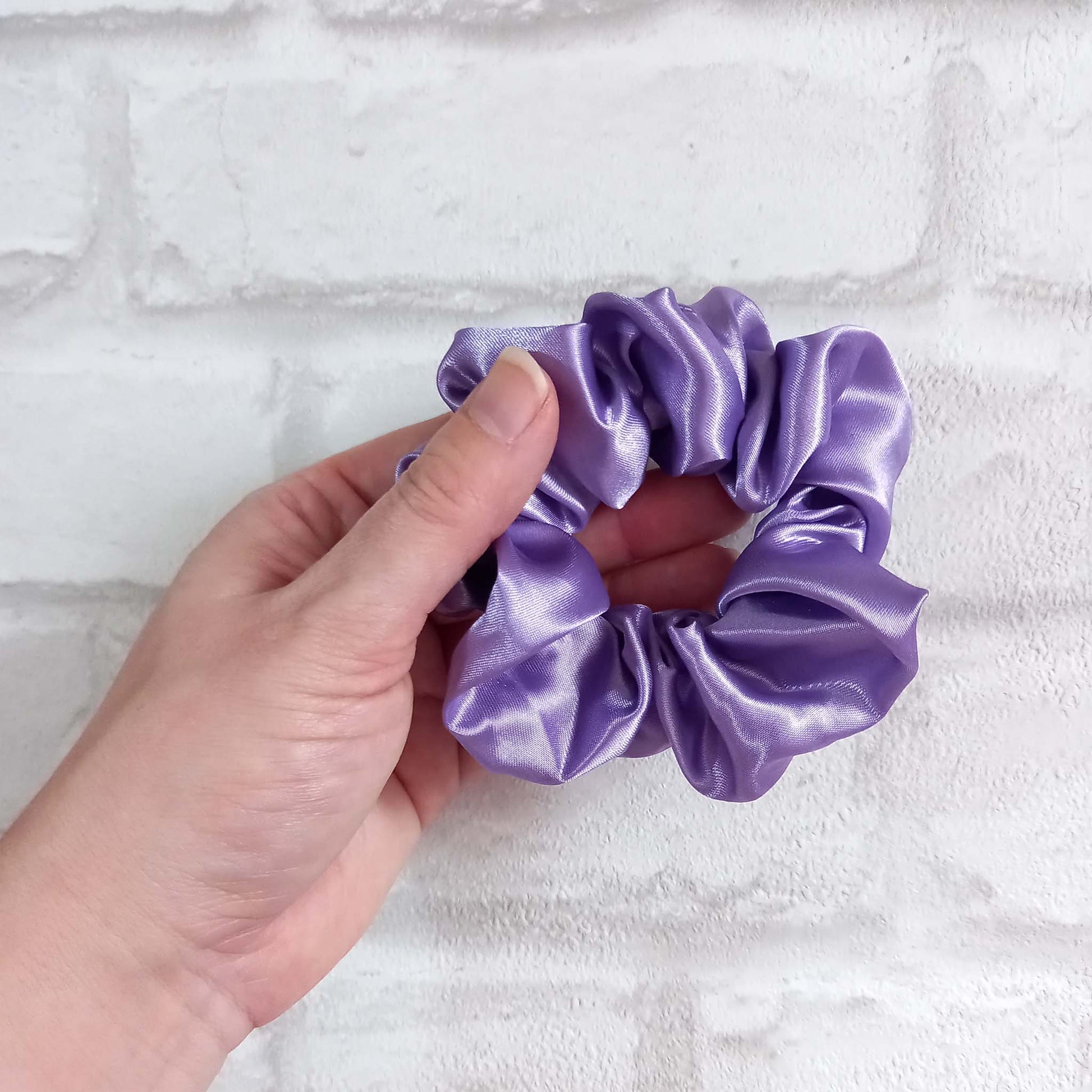 Hand holding a lilac satin hair scrunchie