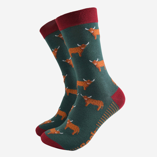 A pair of men’s green and red socks featuring highland cows
