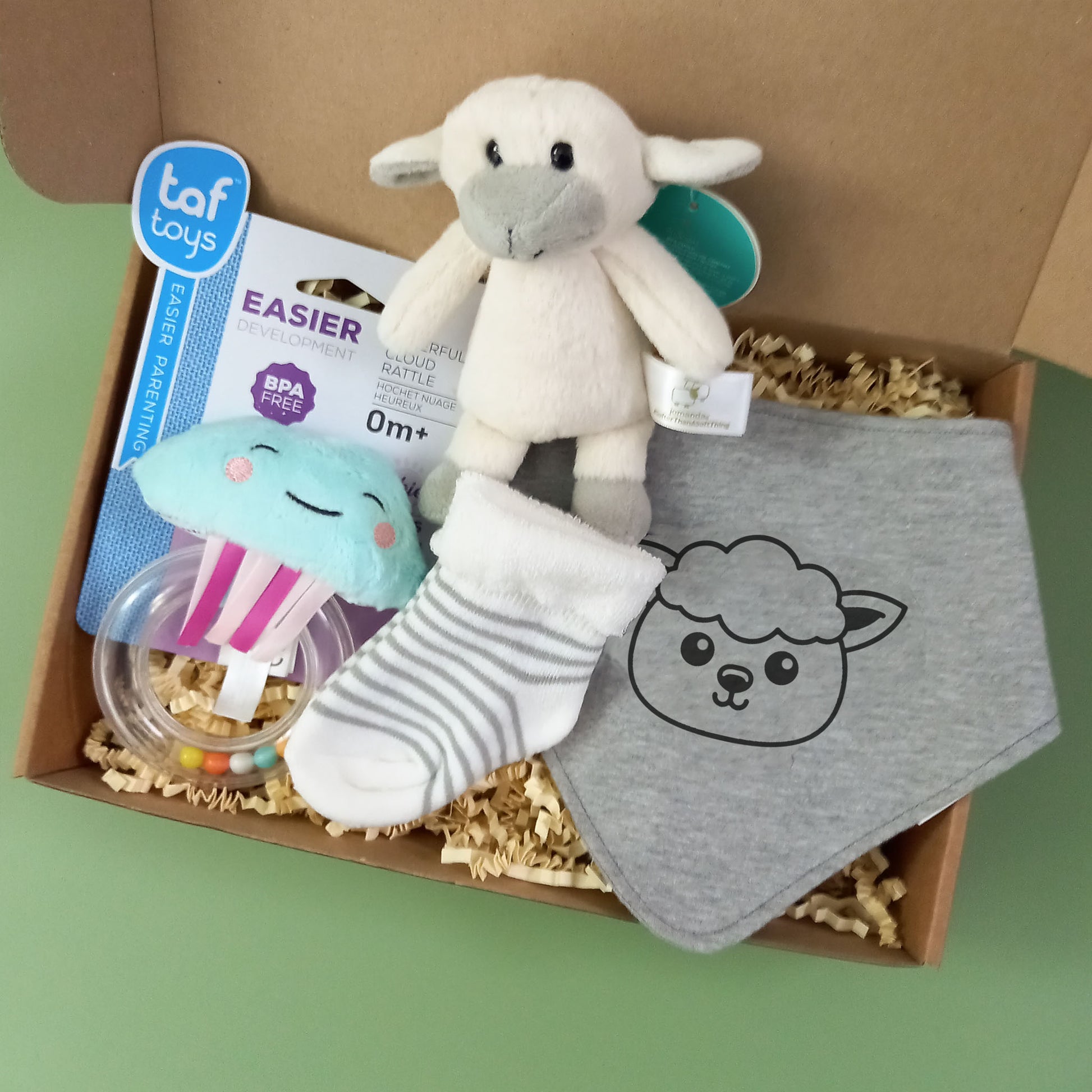 New baby gift box containing a mini soft toy lamb, a pair of baby socks, a lamb themed dribble bib and a cloud shaped rattle