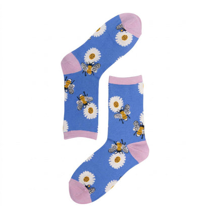 A pair of blue crew socks with pink cuffs and heels, decorated with white daisies and yellow-and-black bumblebees, shown on a plain white background.